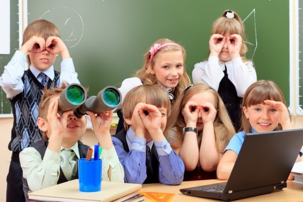 Happy schoolchildren at a classroom looking through binoculars. Education. (photo: )